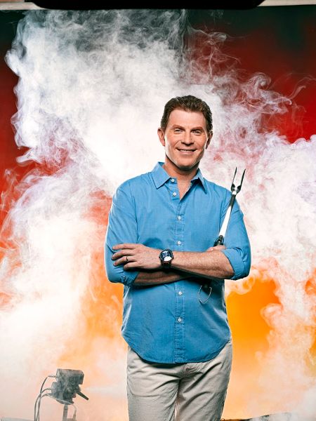 Bobby Flay in a blue t-shirt poses for a picture.